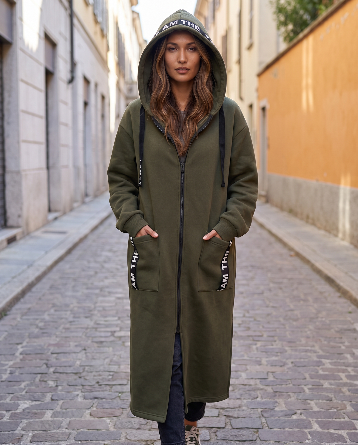 Abrigo sudadera Noa en verde, con la capucha puesta en la calle
