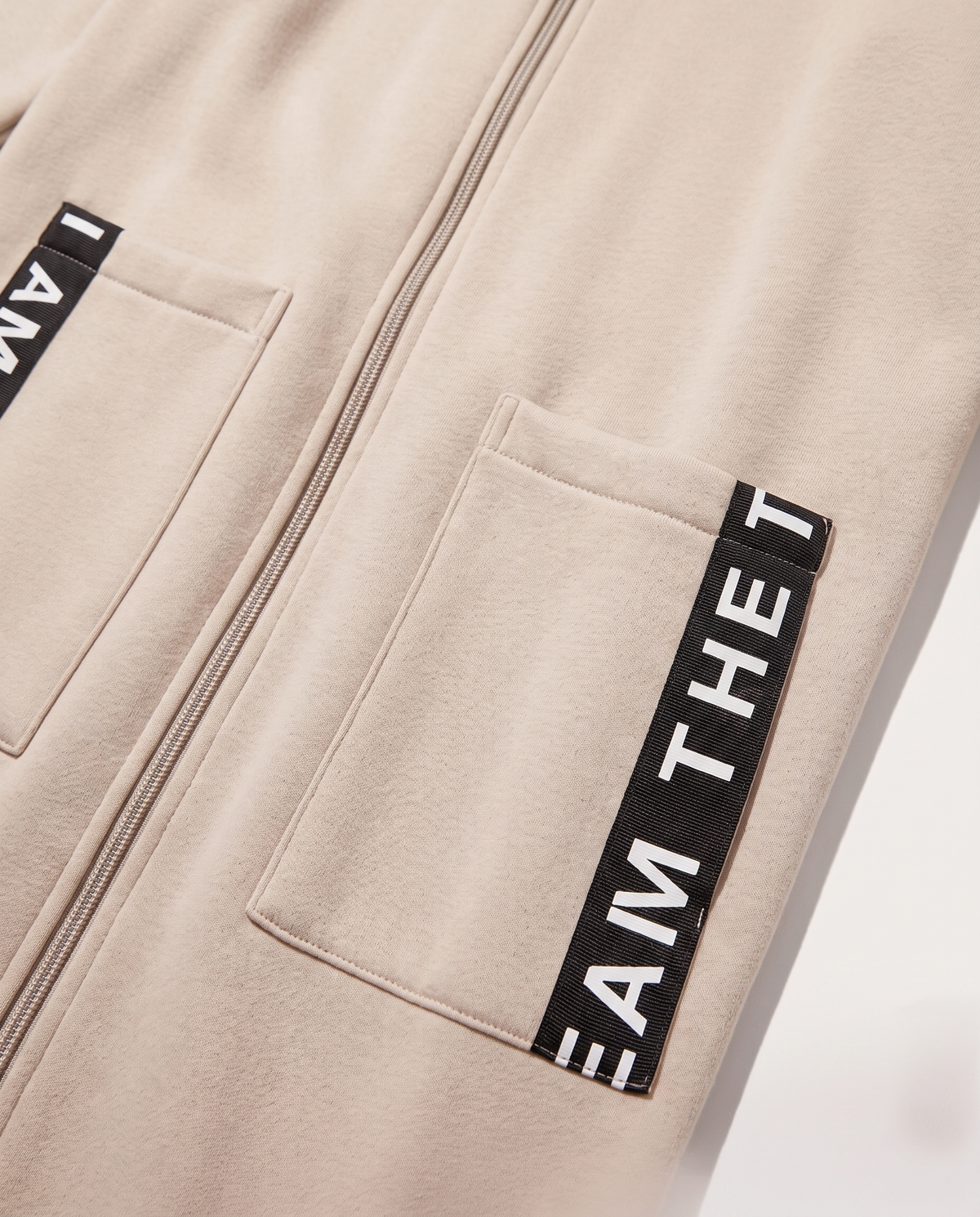 Detalle del tejido de sudadera cepillado, la cremallera y la cinta con letras